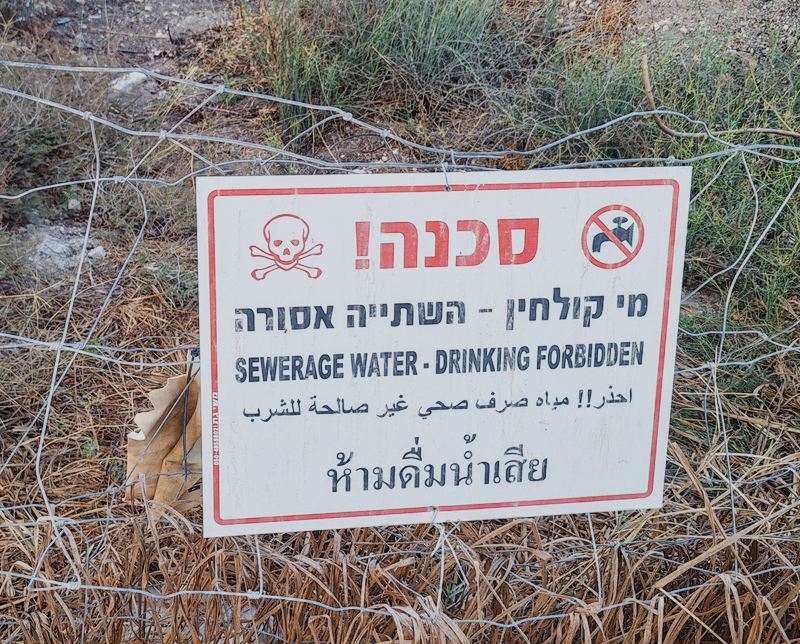 Sign in 4 languages and alphabets warns not to drink from irrigation pipes due to their containing sewage water